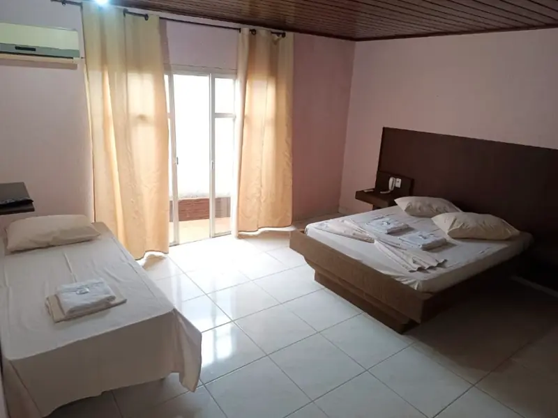 Suíte com cama de casal, cama de solteiro e porta para a área externa